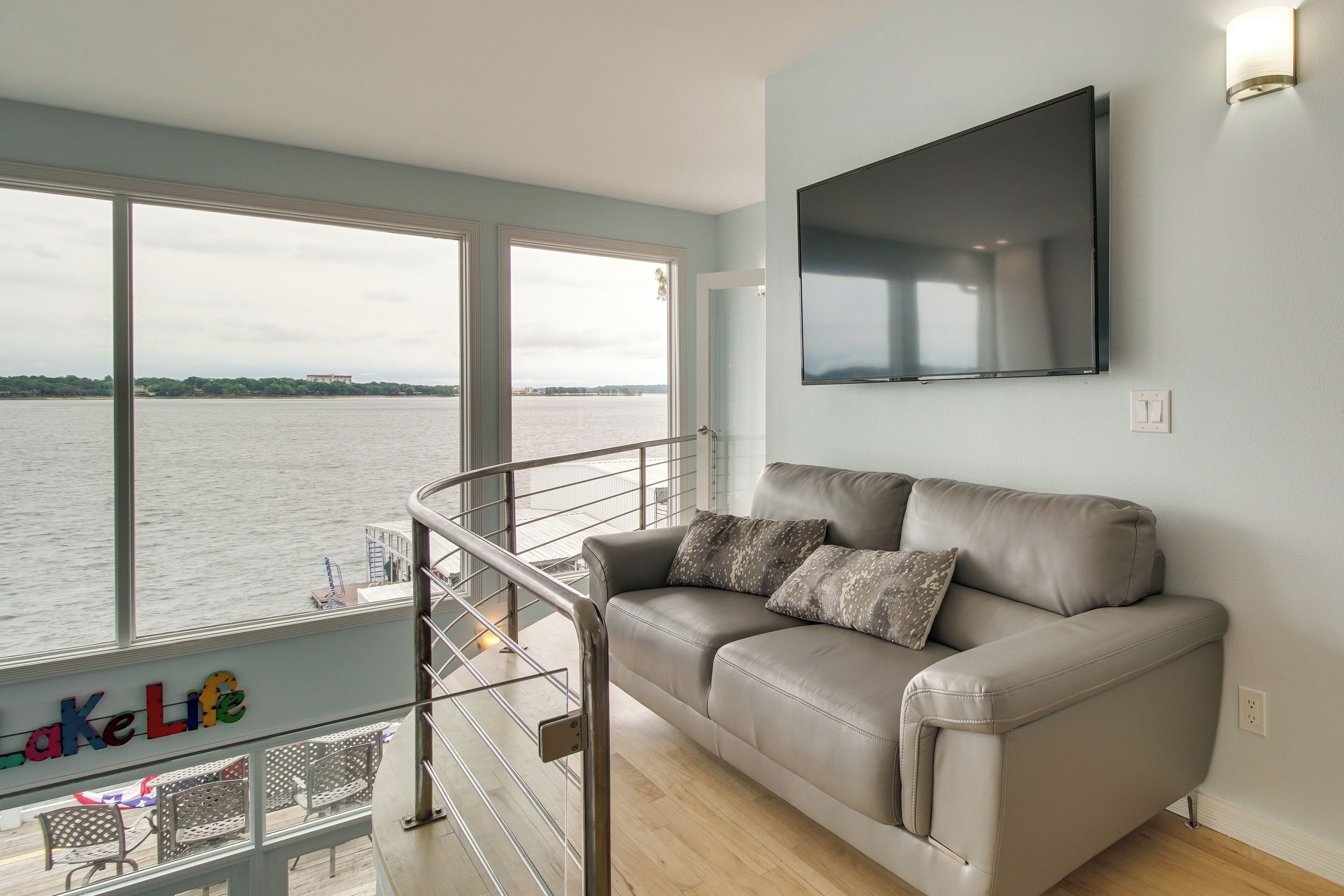 A living room with a sofa, a TV, and a view of a body of water.