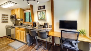 A modern kitchen with wooden cabinets, stainless steel appliances, a built-in microwave, and a coffee station.