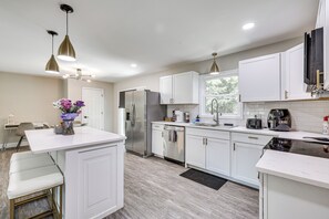 A modern kitchen with white cabinetry, stainless steel appliances, and pendant lighting. - Updated Wilmington Home Near Intracoastal Access (Wilmington)