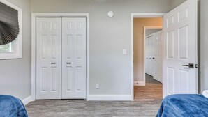 Une pièce dotée de deux portes doubles blanches, d’un ventilateur de plafond et d’un couloir menant à d’autres portes.