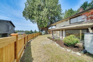 Una proprietà residenziale con recinzione in legno, un albero grande e una casa dal design moderno.