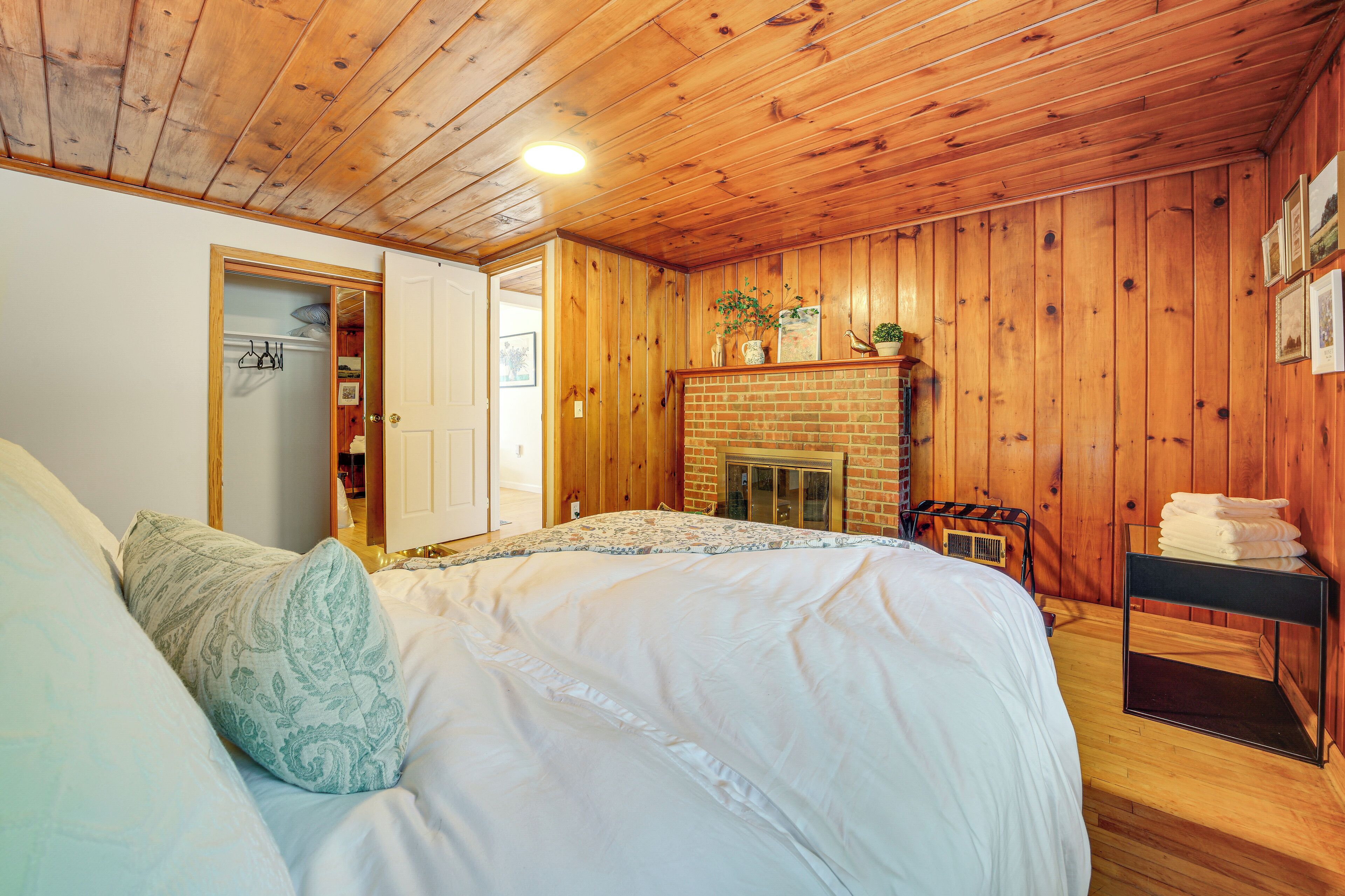 Een slaapkamer met een groot bed, houten wanden, een open haard en een klein tafeltje met handdoeken.