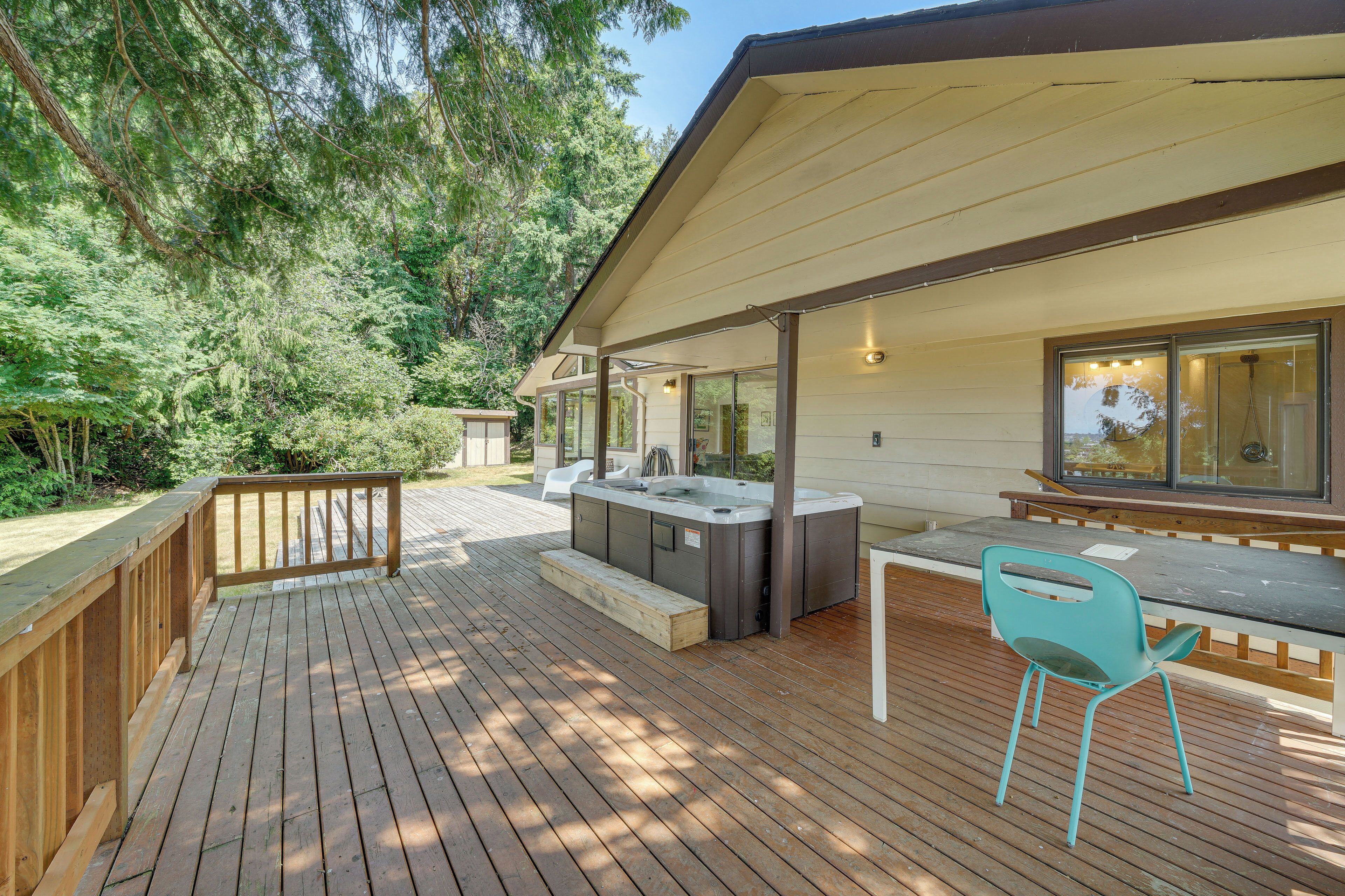 A wooden deck with a hot tub, a table, and a chair.