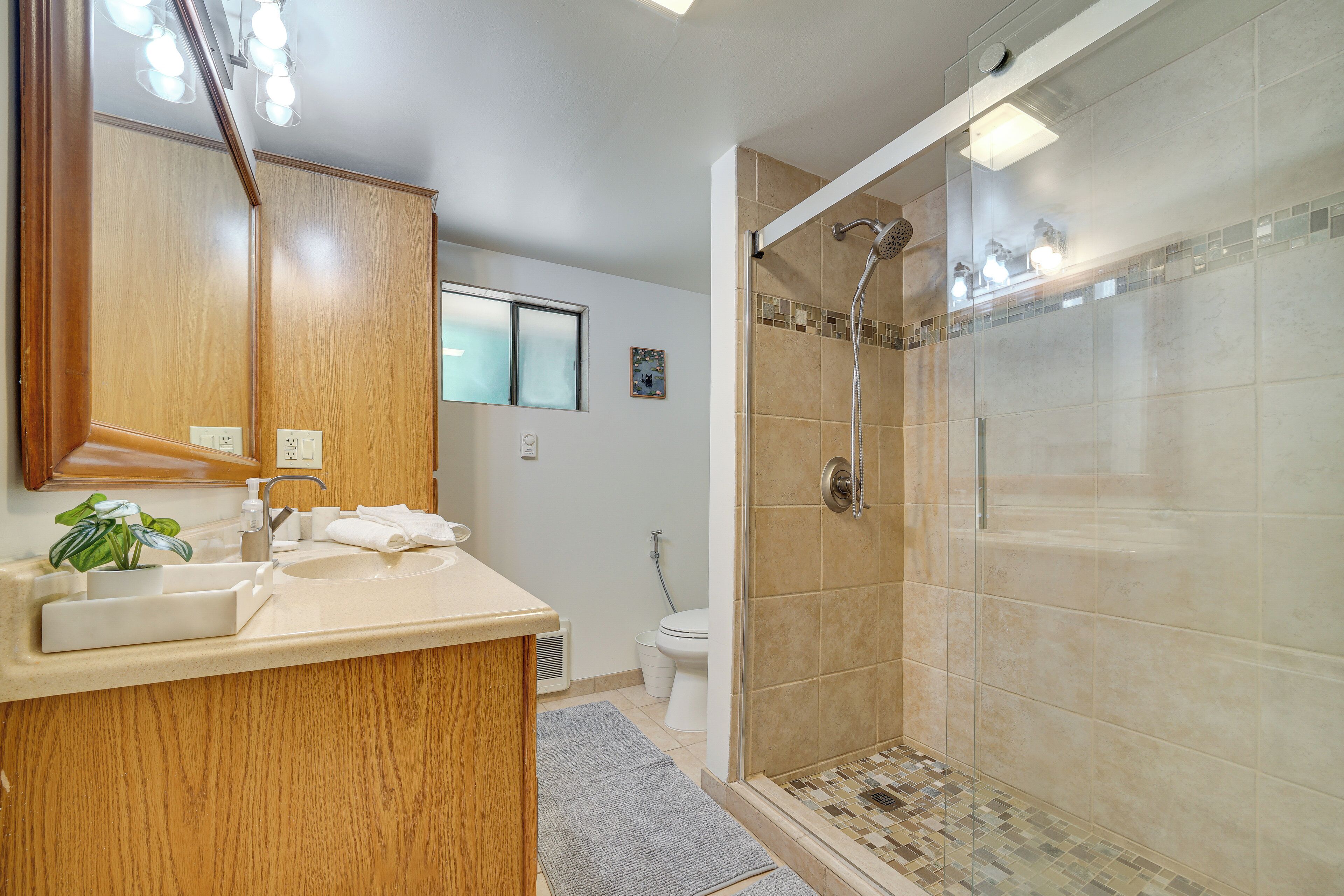 A modern bathroom with a wooden vanity, a glass shower enclosure, and a toilet.