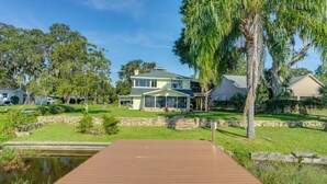 A house with a large deck, a pond, and surrounding greenery. - Dora Canal Views & Shared Dock: Apt in Tavares! (Tavares)