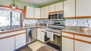 A kitchen with white cabinets, a stainless steel oven, a microwave, and a granite countertop. - Dora Canal Views & Shared Dock: Apt in Tavares! (Tavares)