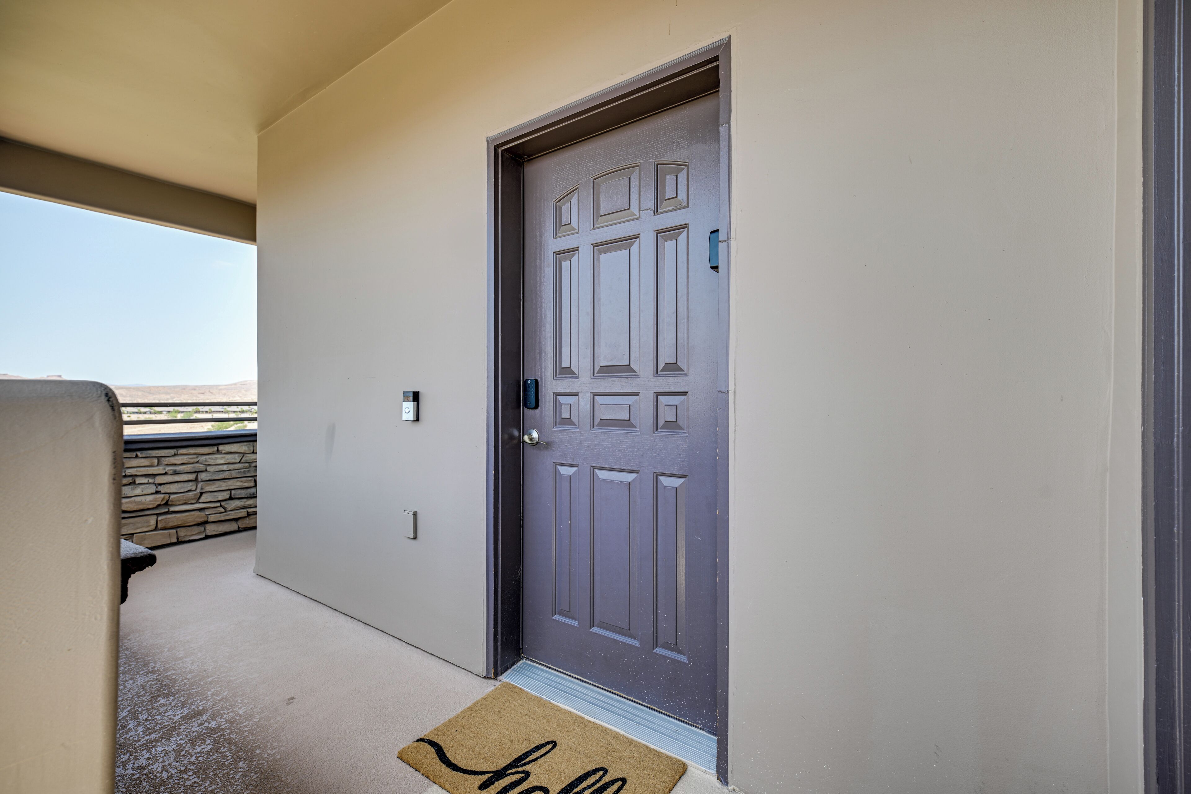 A door with a doormat, a mailbox, and a stone wall in the background.