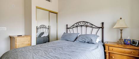 A bedroom with a bed, a wooden nightstand, a dresser, a mirror, and a ceiling fan.