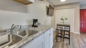 A kitchen with two stainless steel sinks, a coffee maker, and a dining area with a table and chairs.