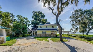 A two-story house with a stone foundation, a balcony, and a view of the water. - Lake Dora Escape: Canal Access & Seaplane Sights! (Tavares)