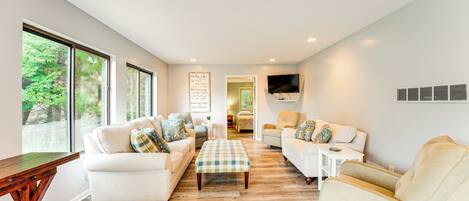 A spacious living room with large windows, a flat-screen TV, and a cozy seating area.
