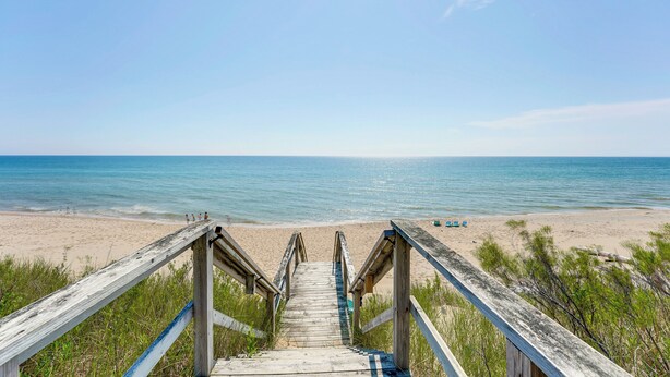 Eine Holztreppe führt zu einem Strand mit freiem Blick auf das Meer.