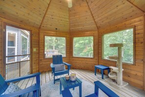 A wooden cabin with a deck, a blue chair, a small table, and a cat tree. - Swim Dock & Game Room: Lakefront Home in Siren! (Siren)