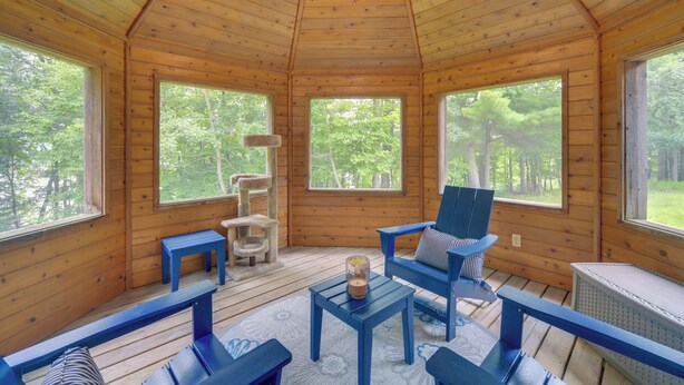 A cabin with a wooden interior, large windows, a cat tree, and blue furniture.