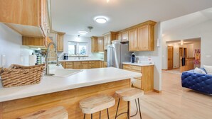 A modern kitchen with wooden cabinets, a white countertop, and a built-in island with stools.