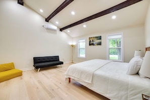 A bedroom with a bed, a yellow sofa, a black sofa, and two windows. - Blue Ridge Retreat on 10-acre Farm: Rural Reset! (Blue Ridge)