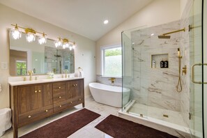 A modern bathroom with a freestanding bathtub, a glass-enclosed shower, and a vanity with a large mirror.