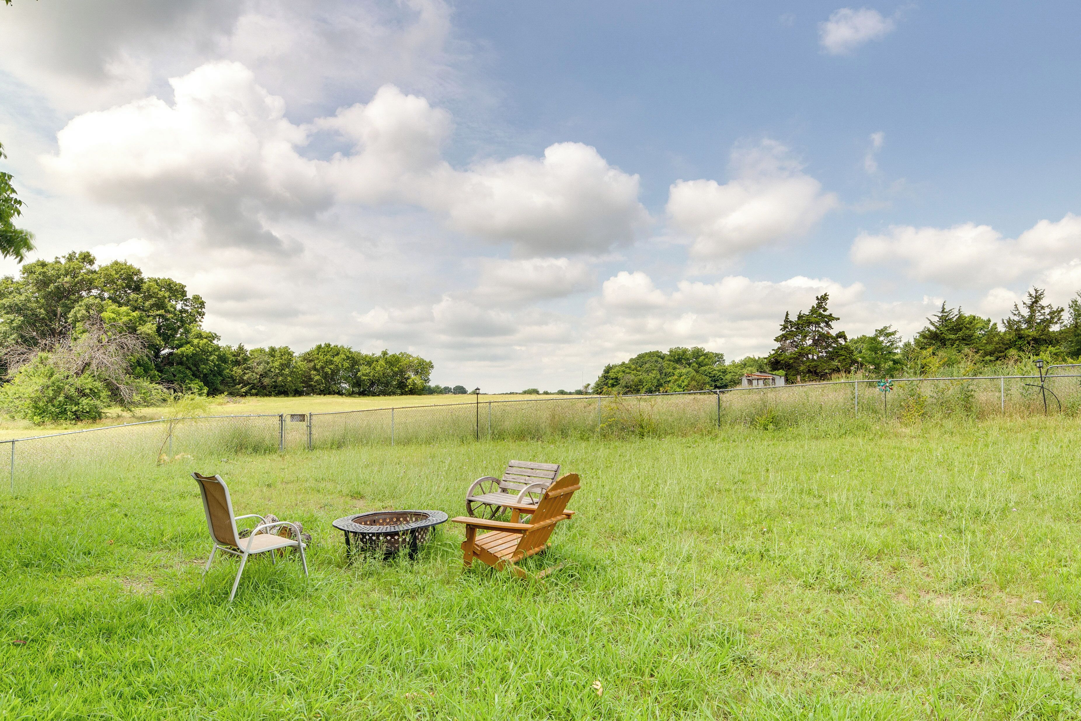 A grassy outdoor area with two wooden chairs and a small round table.