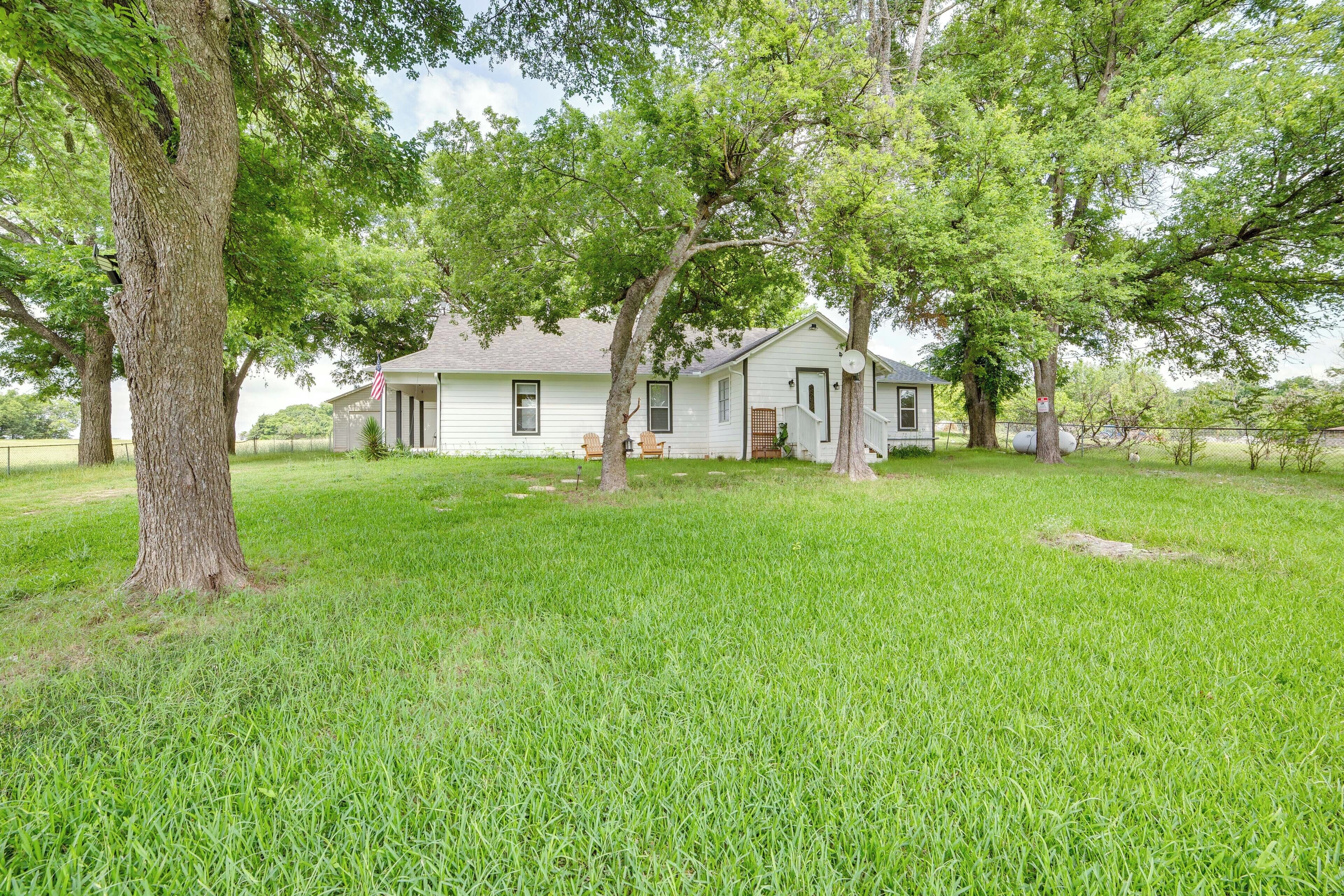 A single-story house with a front porch, surrounded by a well-maintained lawn and large trees.