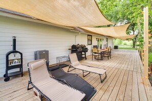 A wooden deck with lounge chairs, a grill, and a barbecue.
