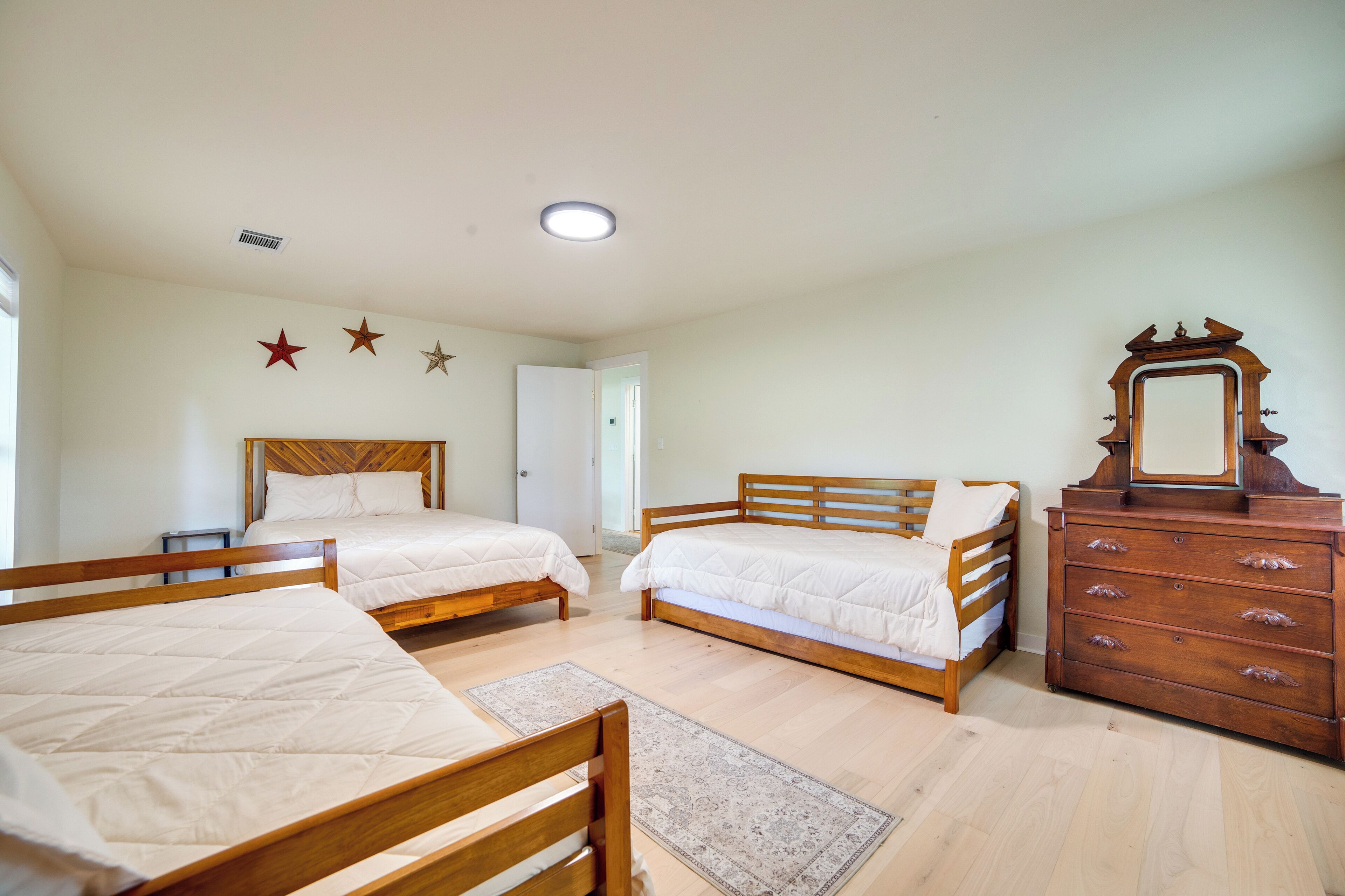 A bedroom with two beds, a dresser, and a mirror.
