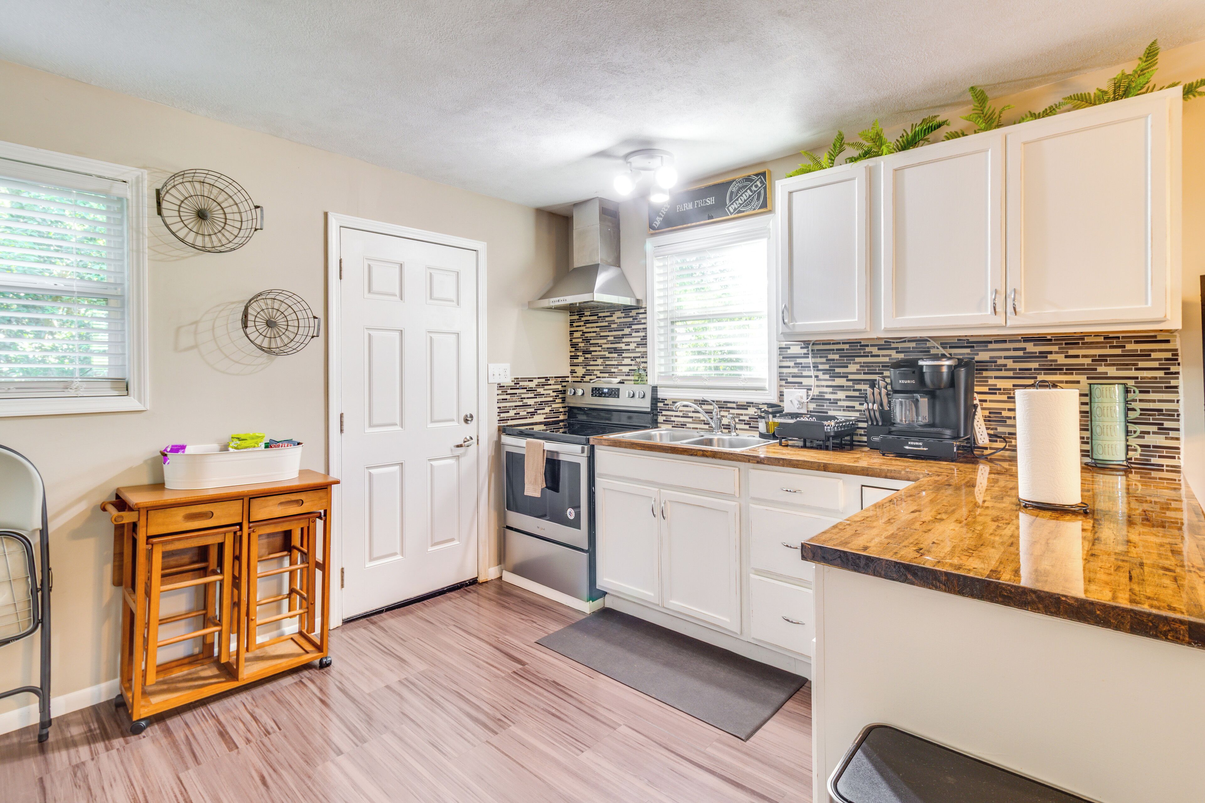 A kitchen with white cabinets, a wooden countertop, a stove, and a sink.