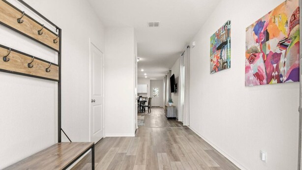A hallway with a bench, wooden floor, and artwork on the walls. - Modern 3BR Home in San Antonio (San Antonio)