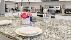A kitchen with granite countertops, white cabinets, stainless steel appliances, and a vase with flowers on the counter. - Modern 3BR Home in San Antonio (San Antonio)