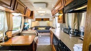 Cocina compacta para autocaravana con comedor, horno integrado y una pequeña zona de estar.