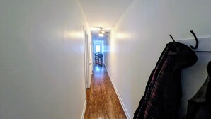 Un pasillo estrecho con piso de madera y paredes blancas.