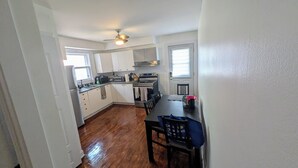 Una cocina compacta con armarios blancos, horno integrado y un comedor con mesa y sillas.