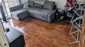 Una sala de estar con un sofá seccional gris, una mesita con un bolso y un cesto de ropa.