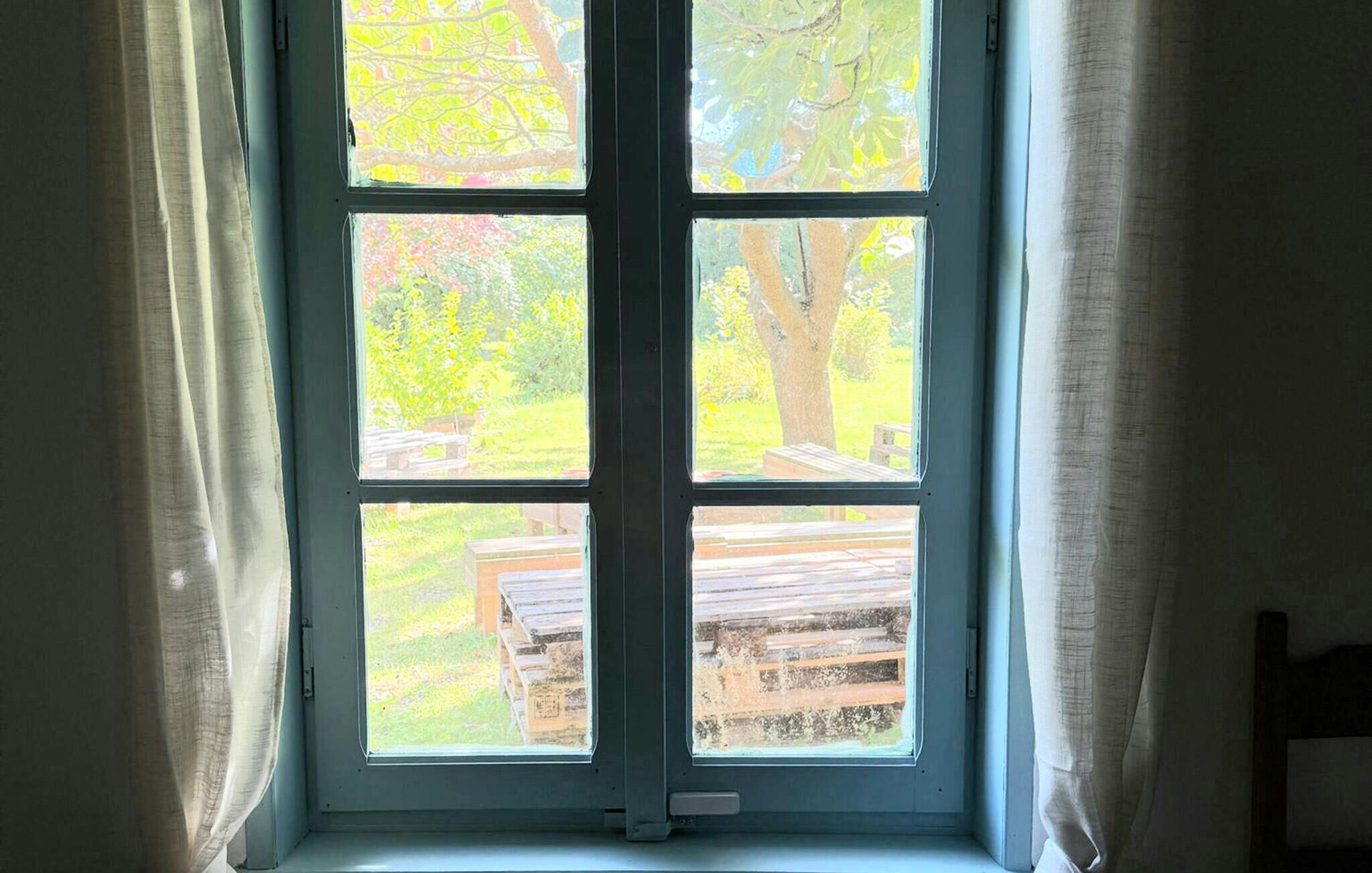 A window with a view of a wooden deck and trees.