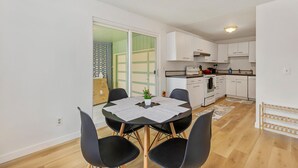 Une cuisine moderne avec des meubles blancs, un plan de travail noir et un coin repas comprenant une table et des chaises.