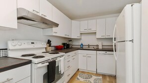 Une cuisine moderne avec des meubles blancs, une cuisinière, un four et un réfrigérateur.