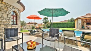 A patio area with a glass table, chairs, and a pool in the background. - Villa Morena (Istria - Kaštel) (Kaštel)