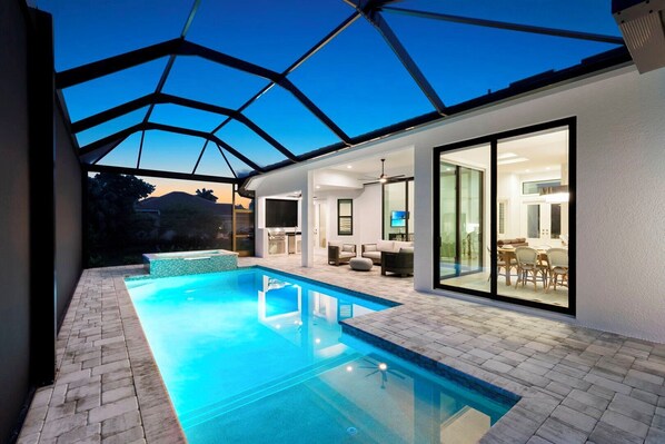 A modern house with a swimming pool, a patio, and a large glass door leading to a dining area. - Tranquil Island Retreat. (Marco Island)