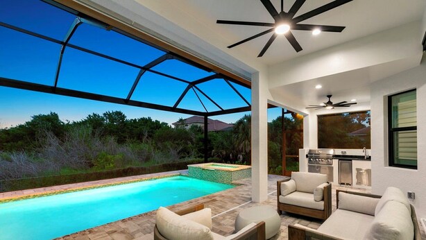 Un espace piscine extérieur moderne, doté d’une structure en verre, de mobilier d’extérieur et d’un barbecue.