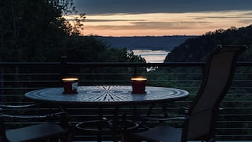 A round table with two candles, surrounded by chairs, overlooking a body of water and hills.