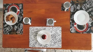 A wooden table with a black and white patterned placemat, two white plates, two white cups, and a single red apple on a white placemat. - Spacious modern apartment, balcony with mountain view, free parking (Pescara)