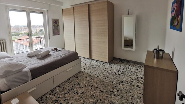 A bedroom with a bed, a wardrobe, a mirror, and a radiator. - Spacious modern apartment, balcony with mountain view, free parking (Pescara)
