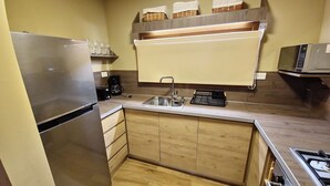 A compact kitchen with a stainless steel refrigerator, a coffee maker, a microwave, and a sink.