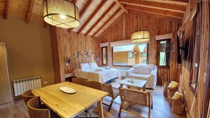 A cozy wooden cabin with a dining area, two bedrooms, and a large window providing natural light.