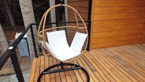 A wicker chair with white cushions on a wooden deck.
