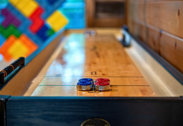 A shuffleboard table with two pucks, one blue and one red, in the foreground.