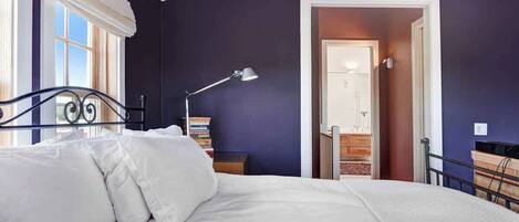 Un dormitorio con cama, mesita de noche, lámpara y estantería.