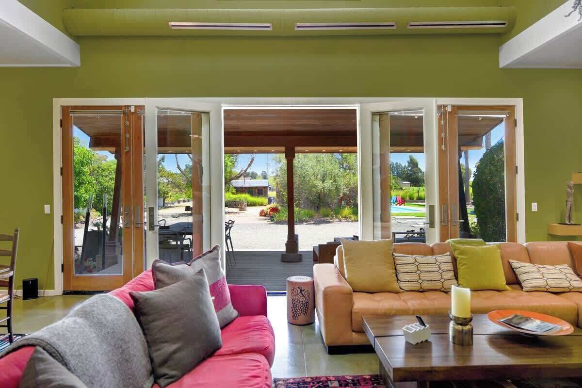 An open-plan living area with a sofa, a coffee table, and a view through glass doors to an outdoor patio.