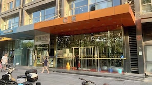 A modern building with a glass facade, a prominent orange awning, and a sign indicating a business or service area. - Beijing CBD - Studio Apartment Queenbeds (Beijing)