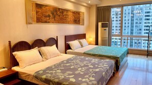 A hotel room with two beds, a large painting on the wall, an air conditioning unit, and a view of a cityscape through the window. - Beijing CBD - Studio Apartment Queenbeds (Beijing)