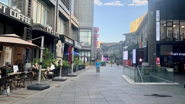 A pedestrian street lined with cafes and shops, featuring outdoor seating and modern architecture. - Beijing CBD - Studio Apartment Queenbeds (Beijing)